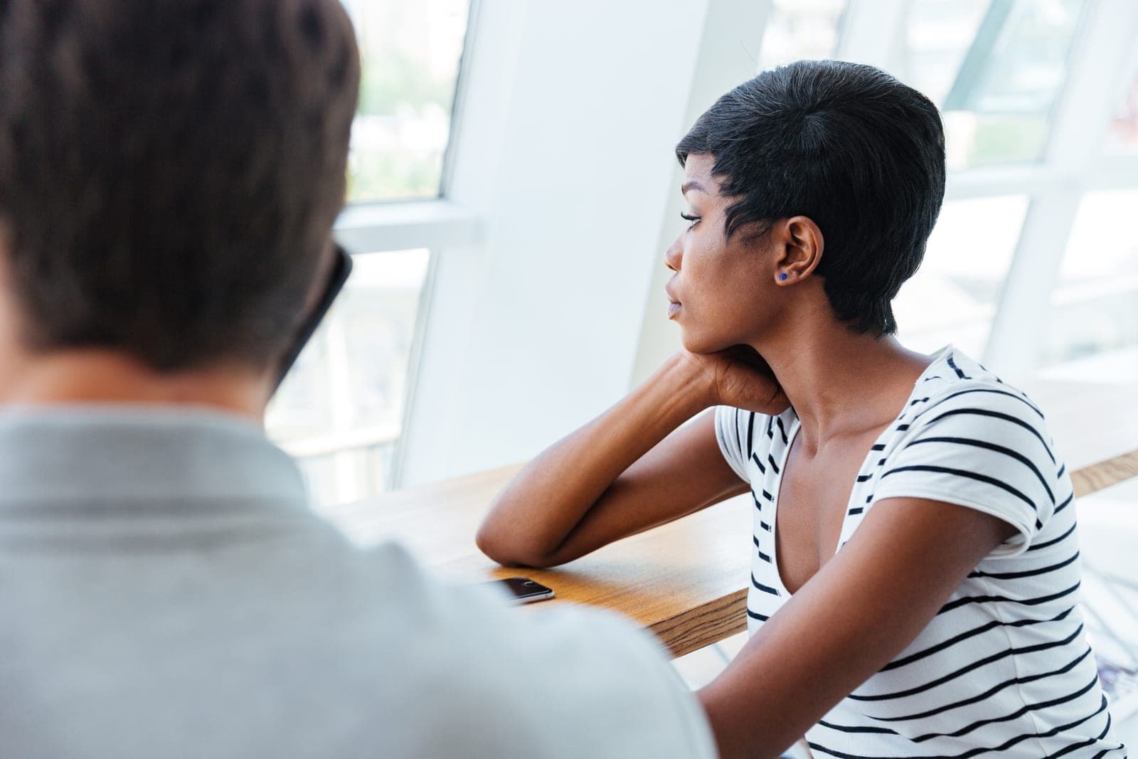 A manager sitting with a colleague who has turned away, tension unspoken between them
